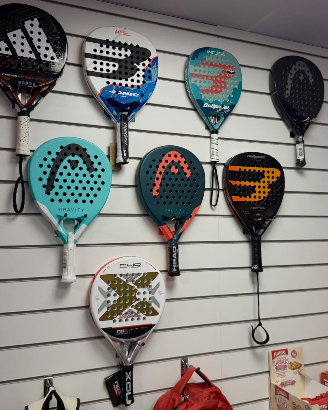 A wall of padel racquets available at the Padel Park pro shop