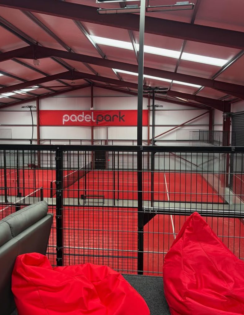 View over the red indoor courts at Padel Park from the chill-out seating area